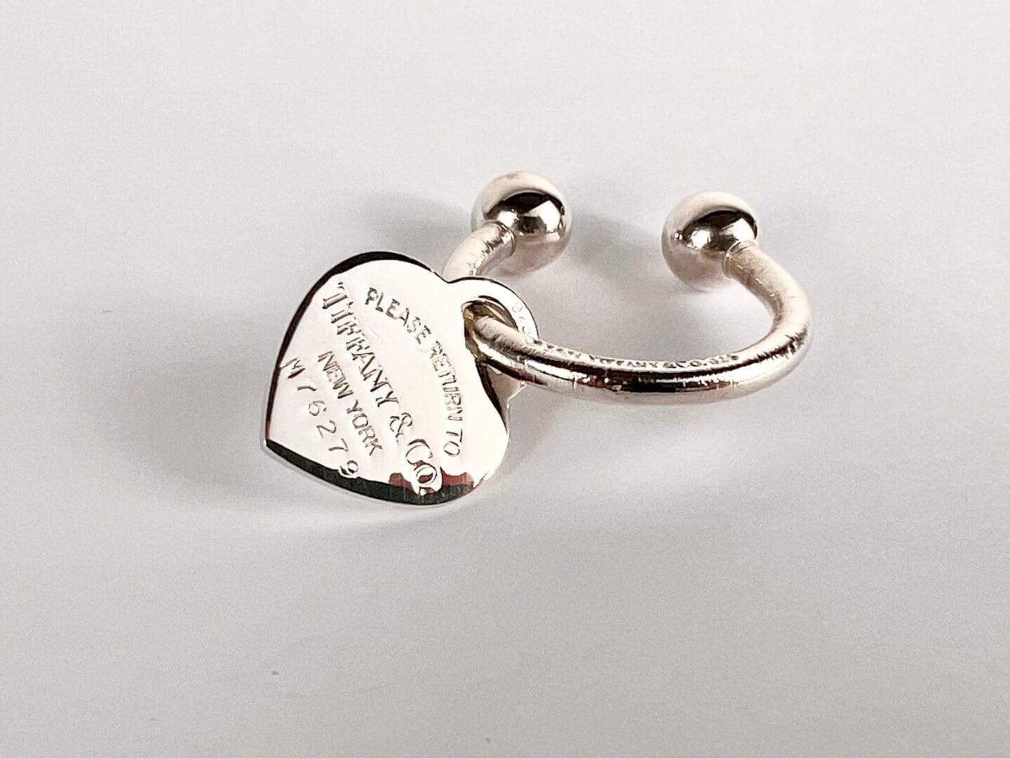 Heart-shaped silver ring with engraved inscription.