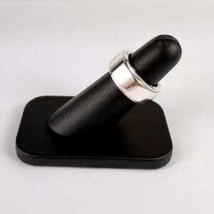 Black ring holder with silver ring displayed.