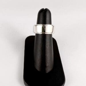 Silver ring on black display stand.