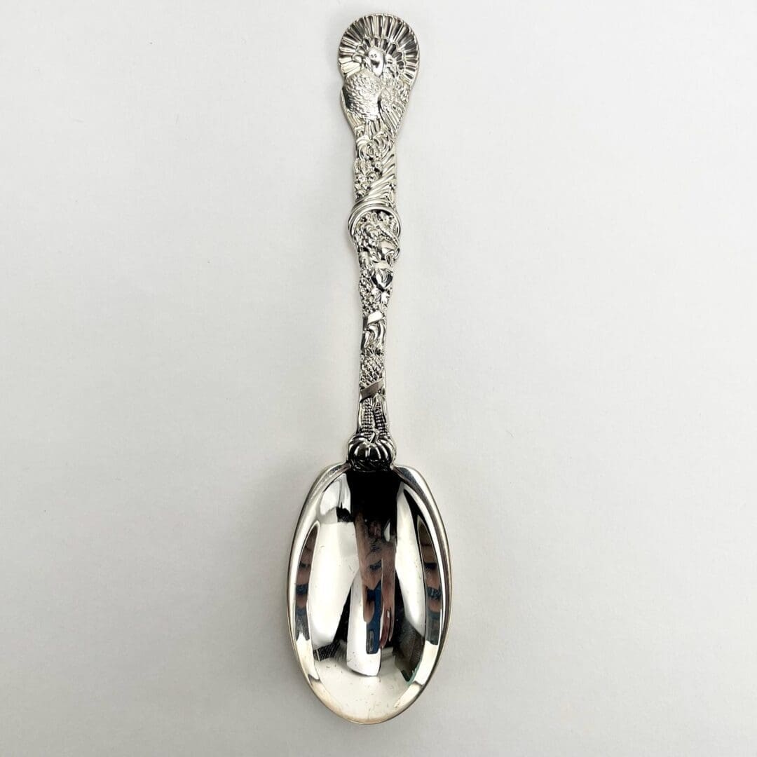 Ornate silver spoon on white background.