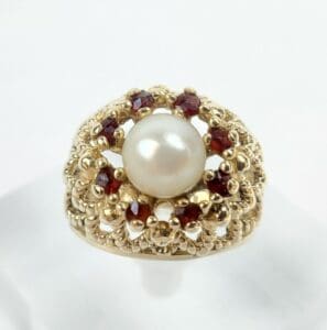 Gold ring with pearl and red gemstones.