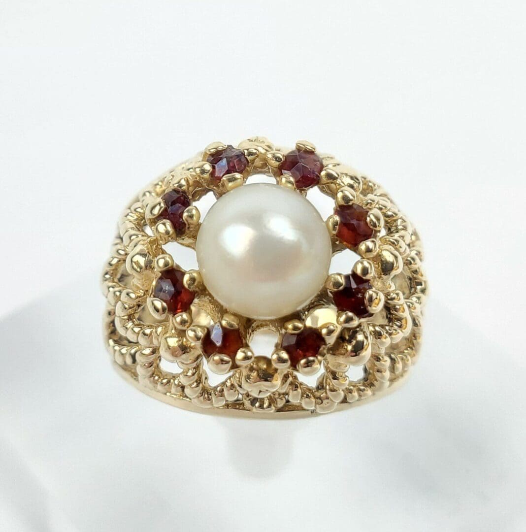 Gold ring with pearl and red gemstones.