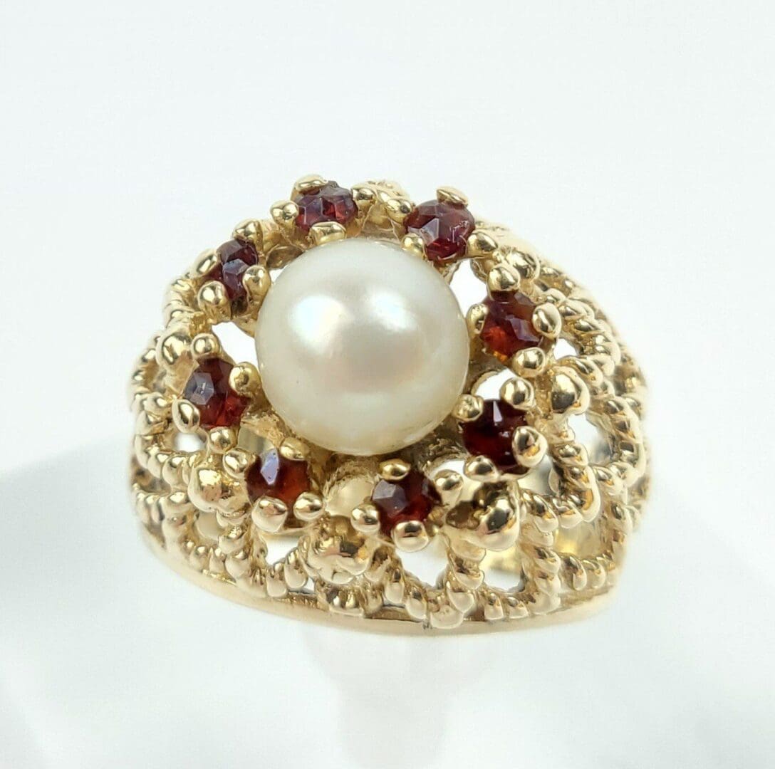 Gold ring with pearl and red gems.