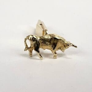 Gold bull-shaped cufflink on white background.