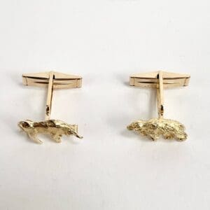 Gold bear-shaped cufflinks on display.