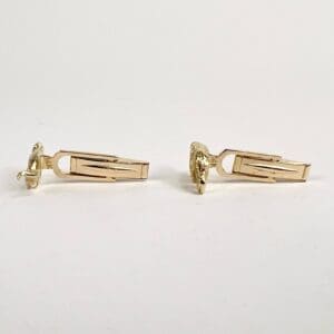 Gold cufflinks on white background.