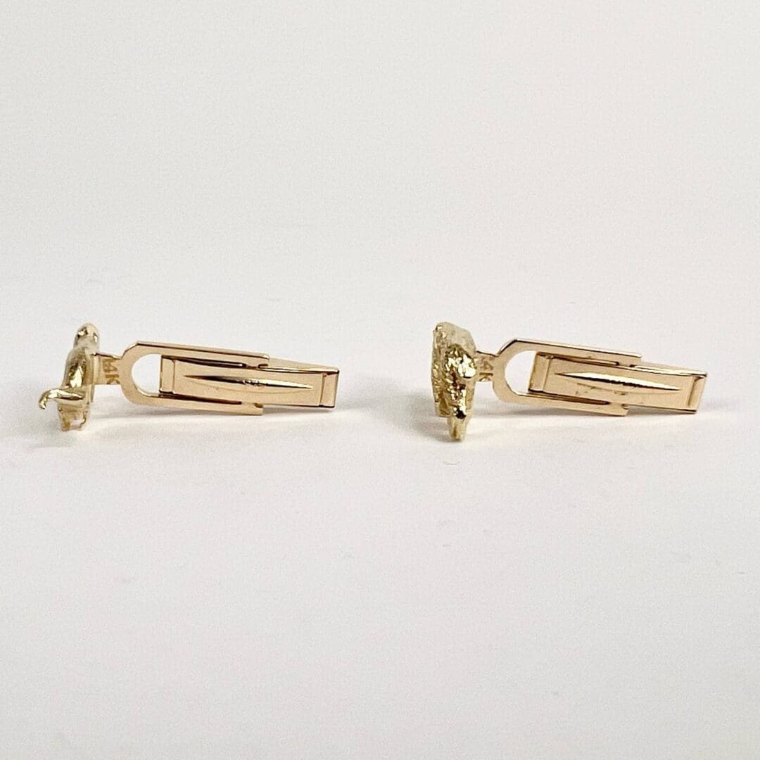 Gold cufflinks on white background.