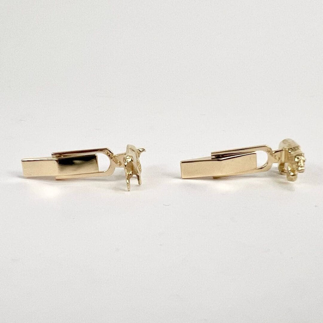 Gold bull and bear cufflinks on display.