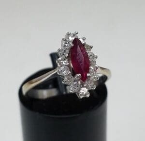 Silver ring with red gemstone and diamonds.