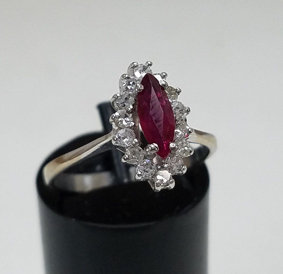 Silver ring with red gemstone and diamonds.