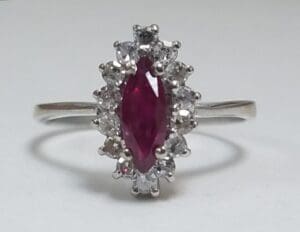 Silver ring with red gemstone and diamonds.