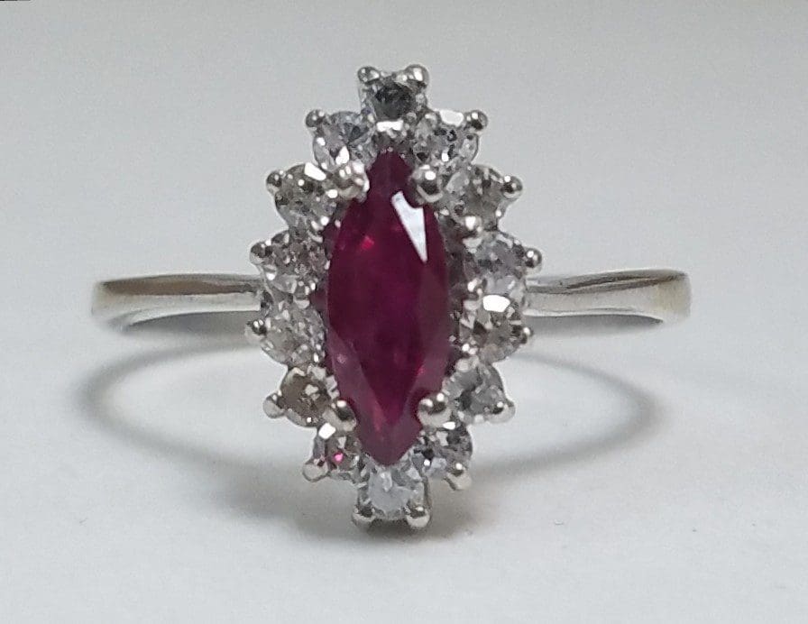 Silver ring with red gemstone and diamonds.