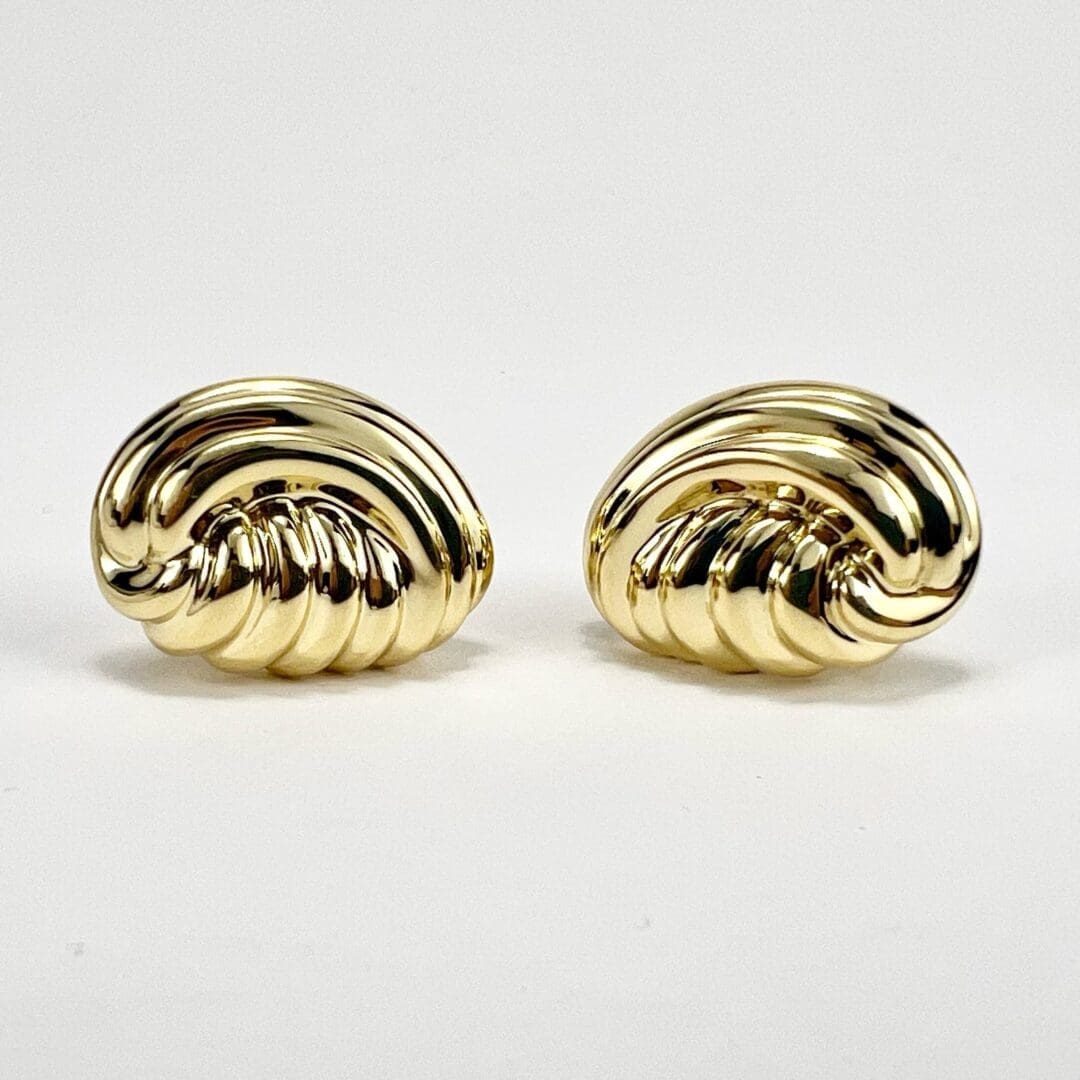 Gold swirl-patterned earrings on white background.