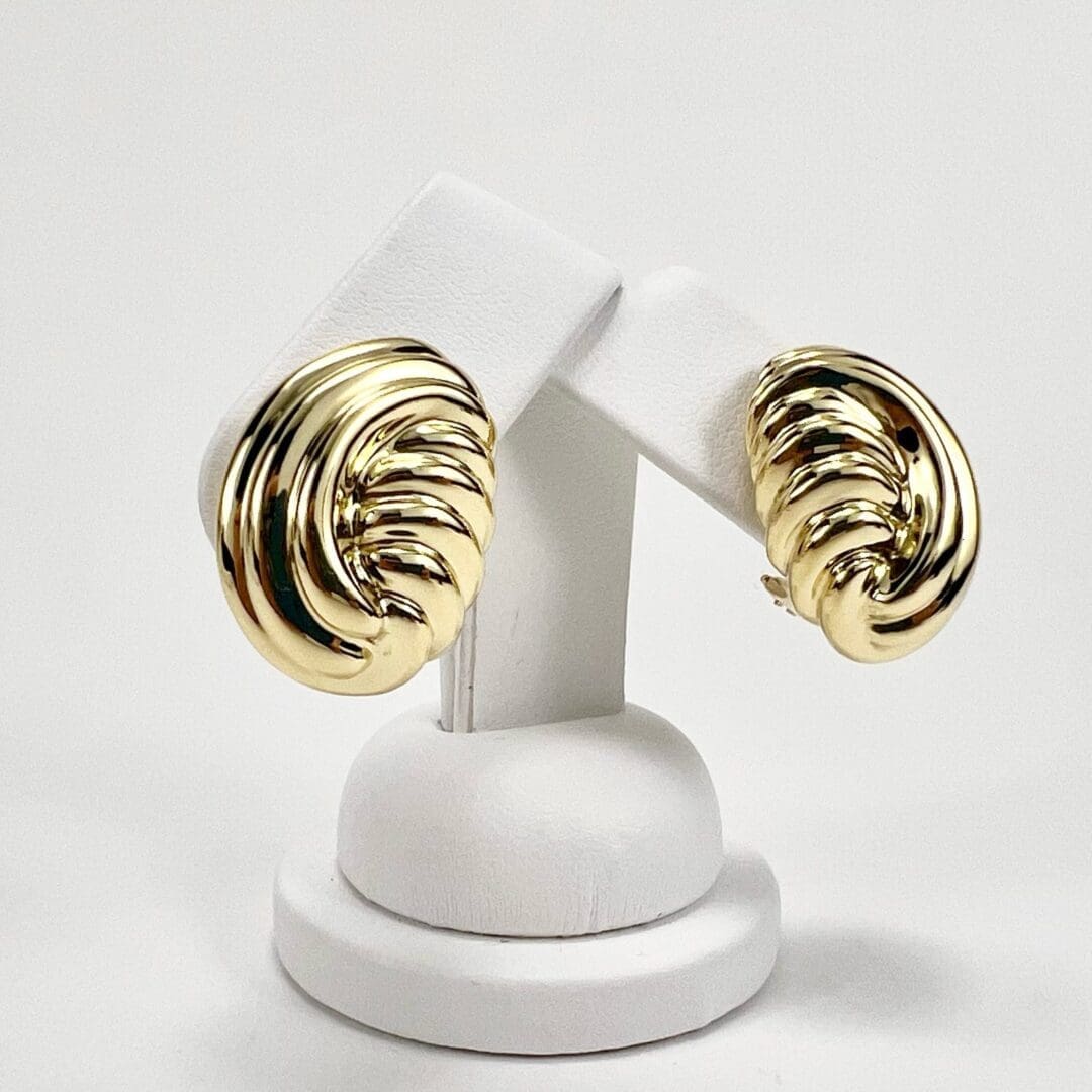 Gold twisted earrings on display stand.