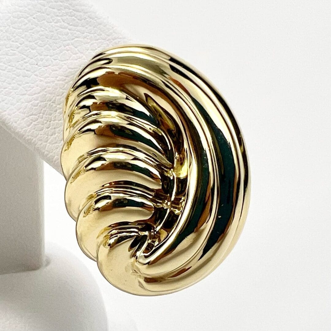 Gold spiral ring on white display stand.