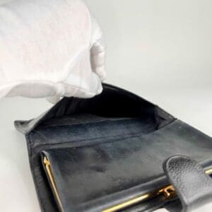 White glove holding open black wallet.