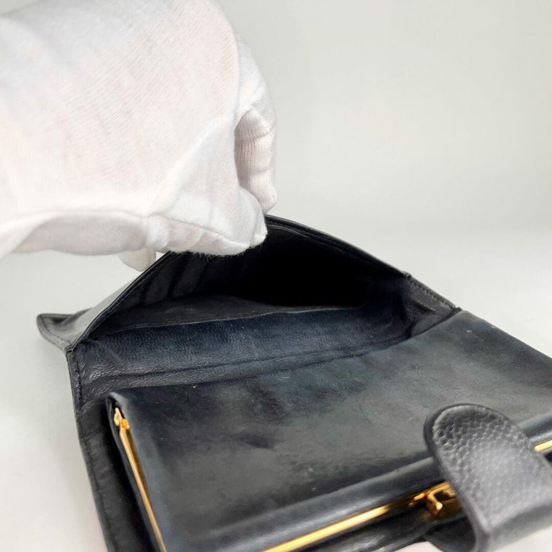 White glove holding open black wallet.