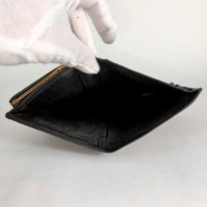 Empty black wallet held by gloved hand.