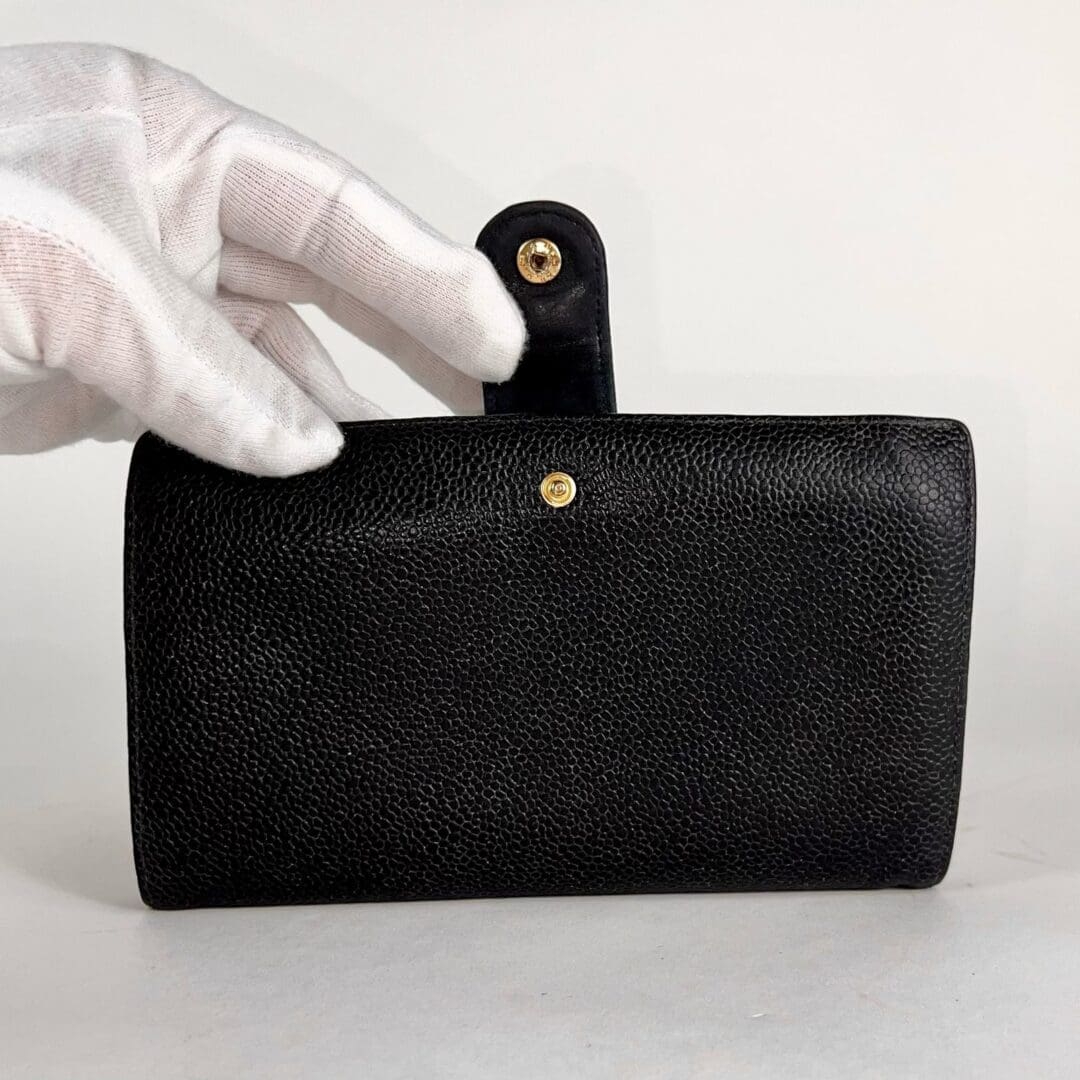 Gloved hand holding a black textured wallet.