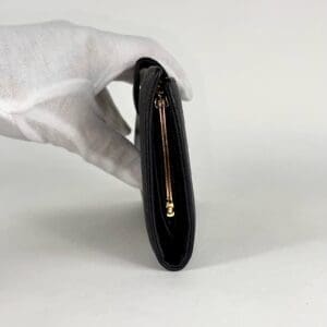 Gloved hand holding a black wallet.