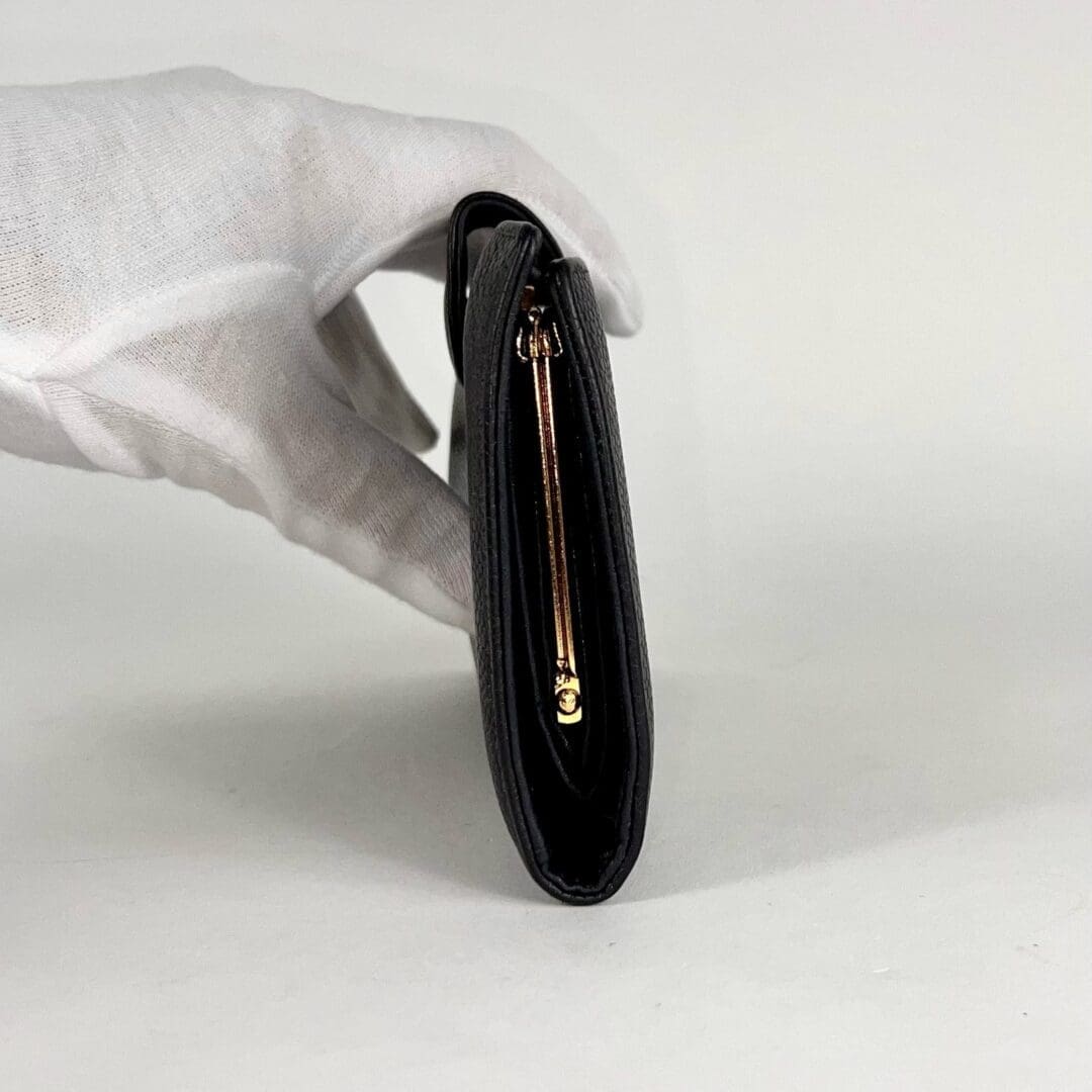 Gloved hand holding a black wallet.