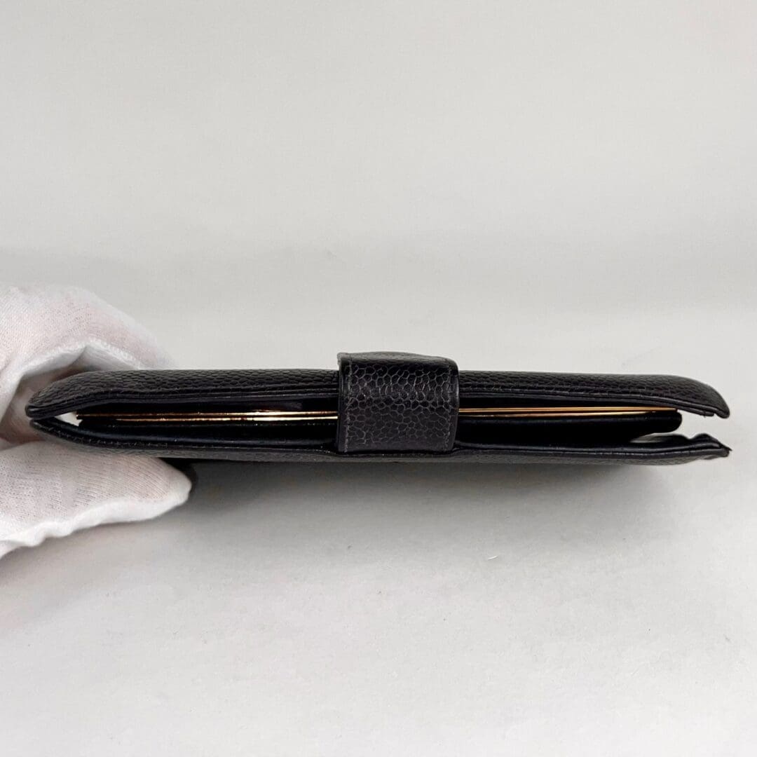 Black leather wallet held by gloved hand.