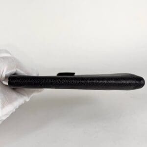Black wallet held by gloved hand.