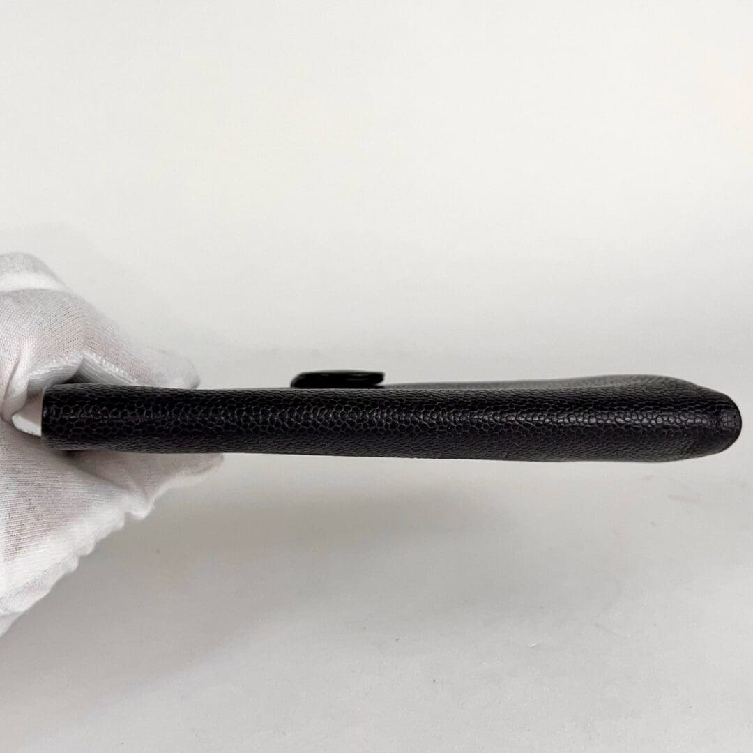Black wallet held by gloved hand.