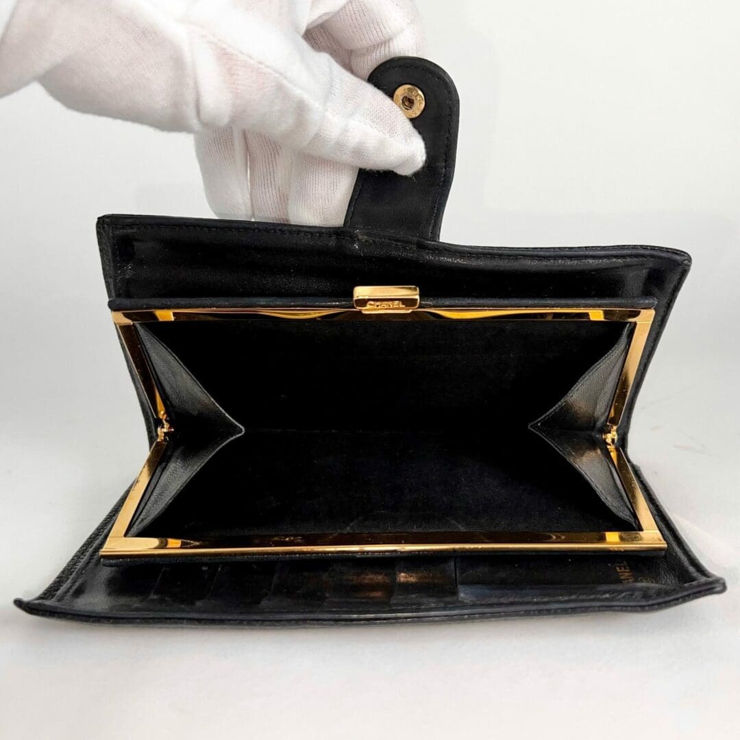 Open black wallet with white-gloved hand.