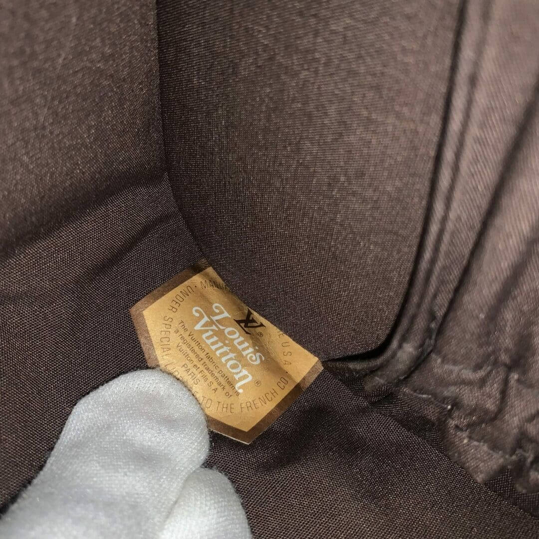 Gloved hand holding Louis Vuitton label inside.