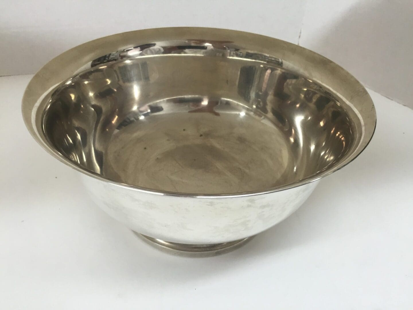 Silver metal bowl on white surface.