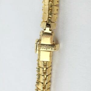 Gold bracelet with clasp on white background.
