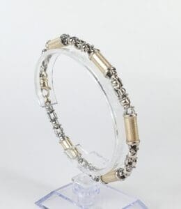 Silver and gold bracelet on display stand.