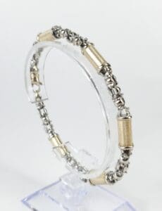 Silver and gold bracelet on display stand.