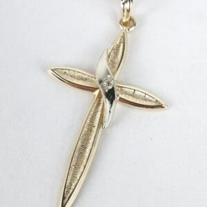 Gold cross pendant with textured design.