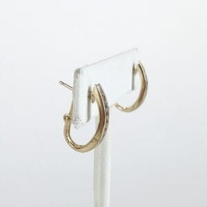 Gold hoop earrings on display stand.