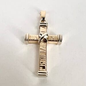 Gold cross pendant with Roman numerals.
