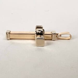 Gold cross-shaped pendant on white background.
