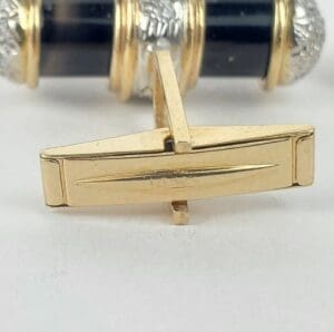 Gold and black cufflink with silver accents.