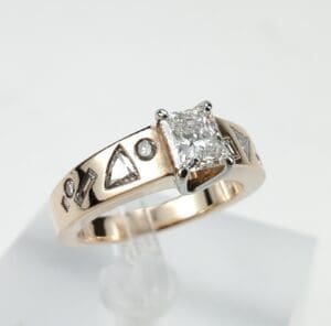 Gold ring with square diamond and symbols.