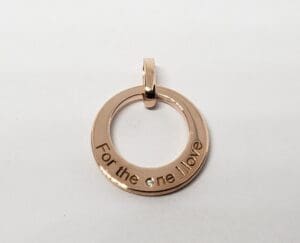 Gold circle pendant with engraved message.