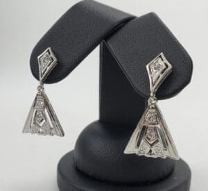 Silver geometric earrings on display stand.