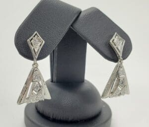 Silver geometric earrings on display stand.