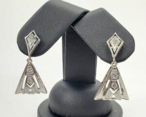 Silver geometric earrings on display stand.