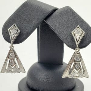 Silver geometric earrings on display stand.