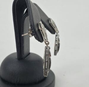 Silver earrings on a black display stand.