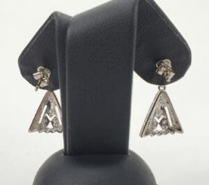Silver triangular earrings on display stand.