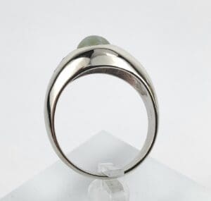 Silver ring with green gemstone on display.