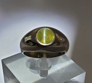 Silver ring with green gemstone on display.