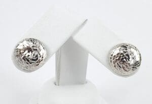 Silver textured round earrings on display stand.